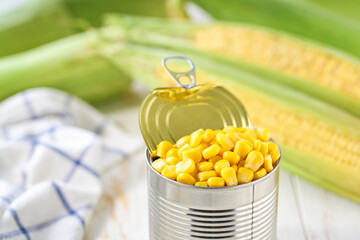 Opened tin can of corn kernels on a white table, selective focus.