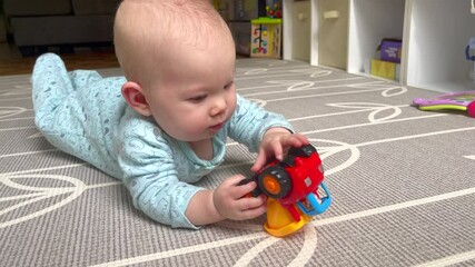 Cute Caucasian newborn baby girl during tummy time playing with a toy. Baby development concept. Baby milestones. Newborn baby with a toy