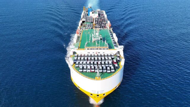 Aerial drone tracking top down photo of roll on roll off or ro ro cargo ship bow with deck designed to carry wheeled cargo cruising outside popular Mediterranean port with deep blue sea 