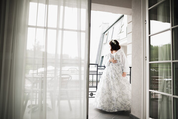 Beautiful bride wearing fashion wedding dress with feathers with luxury delight make-up and hairstyle, studio indoor photo shoot