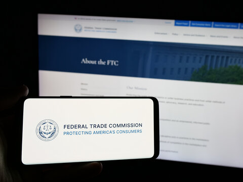 Stuttgart, Germany - 01-24-2025: Person holding smartphone with logo of US government agency Federal Trade Commission (FTC) on screen in front of website. Focus on phone display.