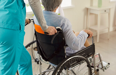 Cropped shot of unrecognizable disabled elderly woman in wheelchair being cared by nurse in clinic undergoes treatment and rehabilitation after serious injury. Senior care concept