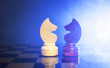 chess pieces of knights on a chessboard on a dark background. © ketrin