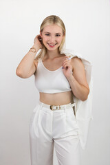 Portrait of a beautiful and smiling young woman in a white top and trousers