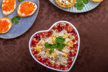 Salad with chicken and pineapples in a heart-shaped salad bowl next to tartlets