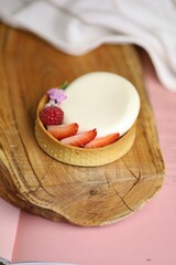 Mini tarte cheesecake with strawberry on a wooden board