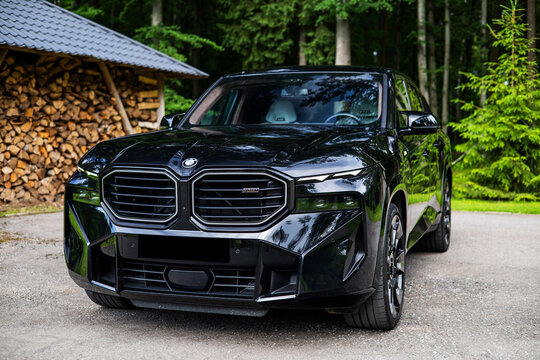 car on the road BMW XM G09 hybrid SUV Detail logo green forest on the background