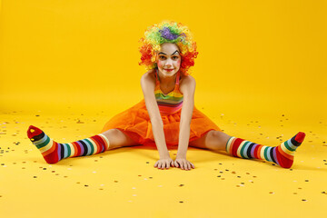 Cute girl dressed like clown and confetti on yellow background. Surprise party