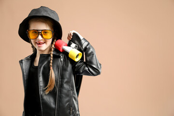 Little girl with penny board on pale brown background, space for text