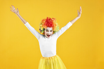 Happy girl dressed like clown on yellow background. Surprise party