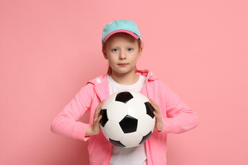 Little girl with soccer ball on pink background