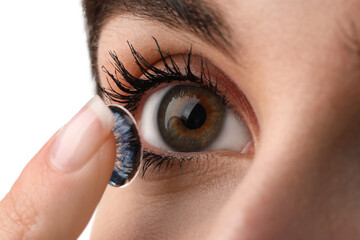 Woman putting in blue color contact lens on white background, closeup