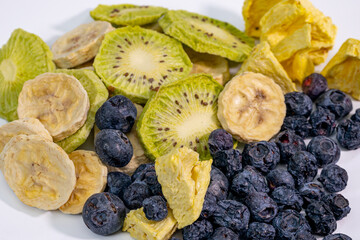 A vibrant assortment of freeze-dried fruits, including slices of kiwi, banana, pineapple, and whole blueberries. Perfect for healthy snacking or culinary use.