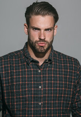 Fototapeta premium Man portrait. Closeup portrait of serious unshaven man in checkered shirt. Sexy male model with stylish hairstyle in plaid shirt. Handsome bearded guy in casual clothes. Fashionable guy with beard.