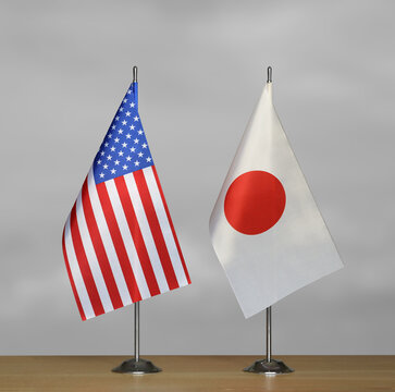 Tabletop flags of USA and Japan on a gray blurred background