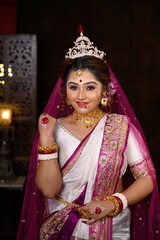Stunning Indian bride wearing traditional bridal saree with heavy gold wedding jewellery, a veil...