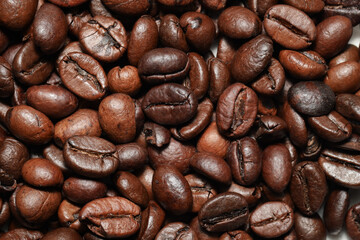 A macro close-up of roasted coffee beans showcasing their rich brown color, detailed texture, and natural oils. The beans are tightly packed, emphasizing their unique shapes and surface patterns.