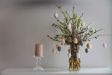 A festive Easter bouquet made of branches adorned with colorful eggs, arranged in a rustic style. The vibrant eggs contrast with the natural twigs, creating a joyful and seasonal atmosphere