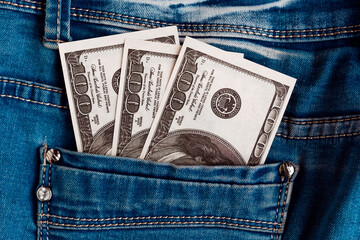 One hundred dollar bills in the jeans back pocket. Dollar banknotes in jeans pocket close-up