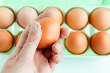 Woman hand holds a raw chicken egg in hand. Food background.