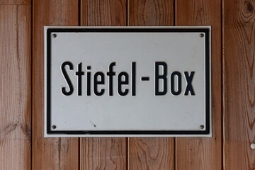 Hinweisschild, an Holzwand, Schild, Stiefel-Box, Stiefelbox, Blechschild, Weiß mit schwarzer Schrift