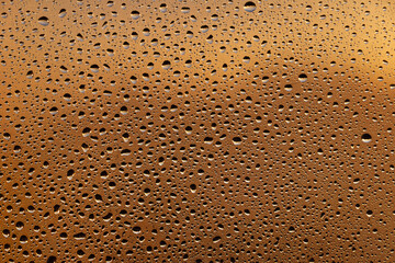 Close up macro many raindrops on muddy glass of sunset orange window at home