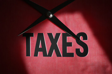 TAXES text on a sheet and scissors: tax cut concept 
