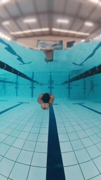 Professional swimmer works out underwater in a public pool and trains freediving no fins discipline, DNF, dynamic no fins