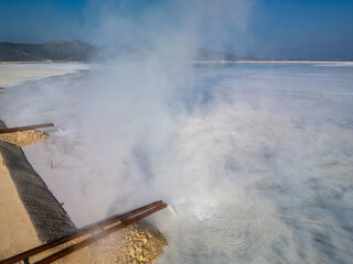A tailings lake of a cement factory with pipes visibly discharging waste into the water. This...
