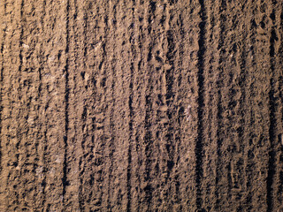 Freshly plowed soil with evenly spaced furrows, creating a textured pattern across the surface. The...