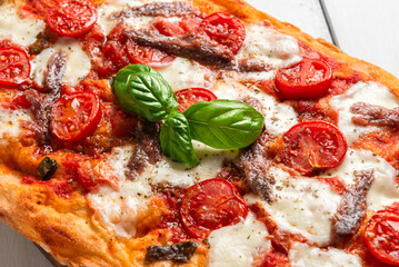 Pinsa romana condita con pomodorini e alici, cibo italiano 