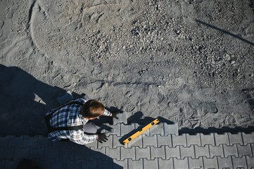 Professional paver worker lays paving stones in layers for pathway, Labor and industry concept