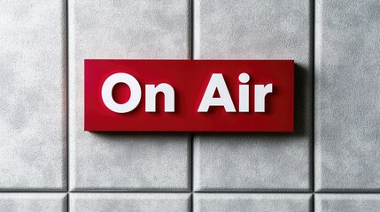 Obraz premium Red 'On Air' sign on a textured wall; broadcasting studio background; for media or broadcast use