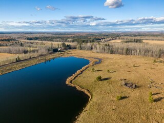 High-angle view of a serene lake nestled within a landscape of forests and fields. Highway visible in distance. Autumn colors. , Nojack, Alberta, Canada