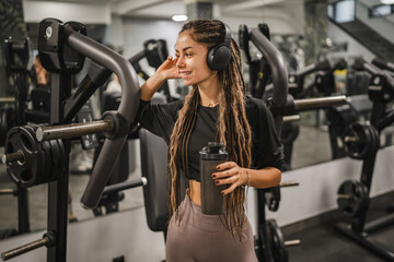 young woman with headphones hold shaker and take a break from exercise