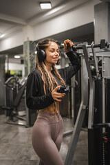 young woman with headphones hold shaker and take a break from exercise