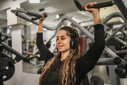 young woman in sportswear do shoulder exercise at the gym machine