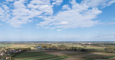 Stunning panoramic view of green fields and blue skies with fluffy clouds, ideal for landscape lovers or nature-themed projects.