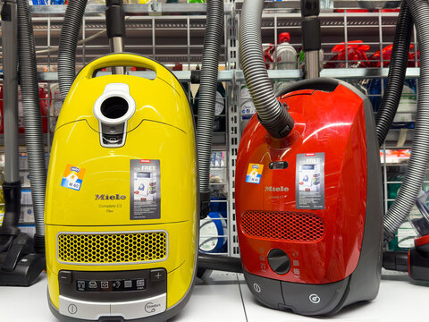 Yellow and red miele vacuum cleaners displayed in appliance store