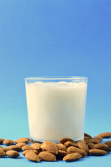 Vertical shot. Almond milk, natural almonds scattered next to the glass cup.