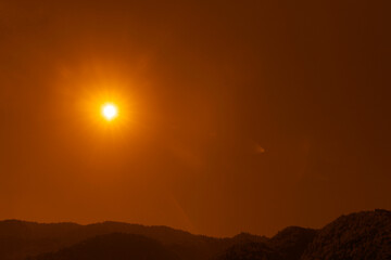 Distant mountain peaks layers at sunrise. Pattern of mountains silhouettes against orange sky in Caucasian mountains. Mountain Peak Sunset. peak covered pine forest. sun rays sunbeams, sunshine in sky