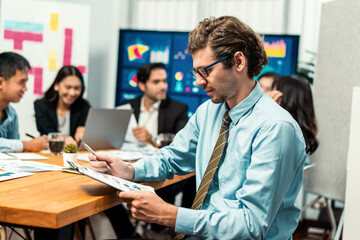 Portrait of businessman or analyst looking at camera with his colleague analyzing data analysis in dynamic business strategy investment planning meeting. Meticulous