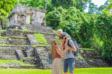 Mom, dad and baby son exploring the ancient pyramids of Palenque, Mexico, surrounded by dense...