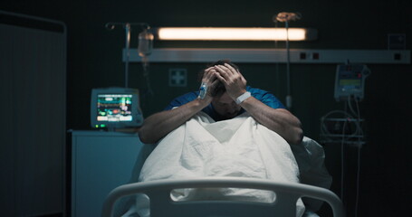 Exhausted tired man with headache suffering from migraine holding head with hands sitting on...