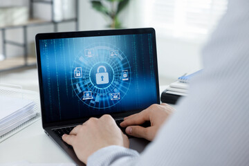 Cyber security. Man using laptop at white table indoors, closeup