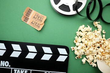 Movie clapper, tasty popcorn, tickets and film reel on green background, flat lay