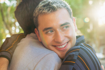 young latin gay man hugs his partner warmly and smiling, gen z