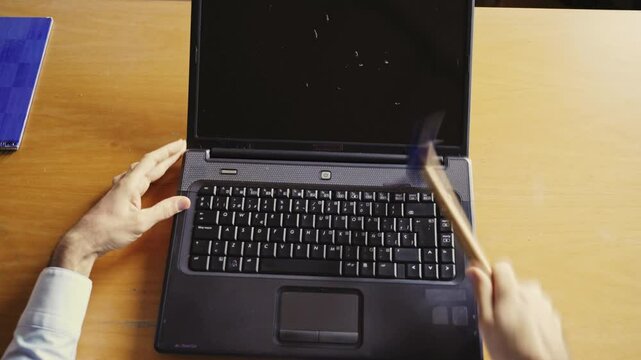 Anger management issues. Male rage. Tech fail. Tecnhnical problems. Top view of man smashing laptop with hammer