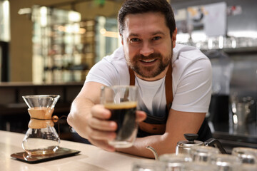 Barista suggesting cup of aromatic filter coffee in cafe, selective focus