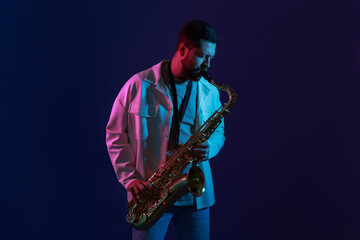 Professional musician playing saxophone on color background with neon lights